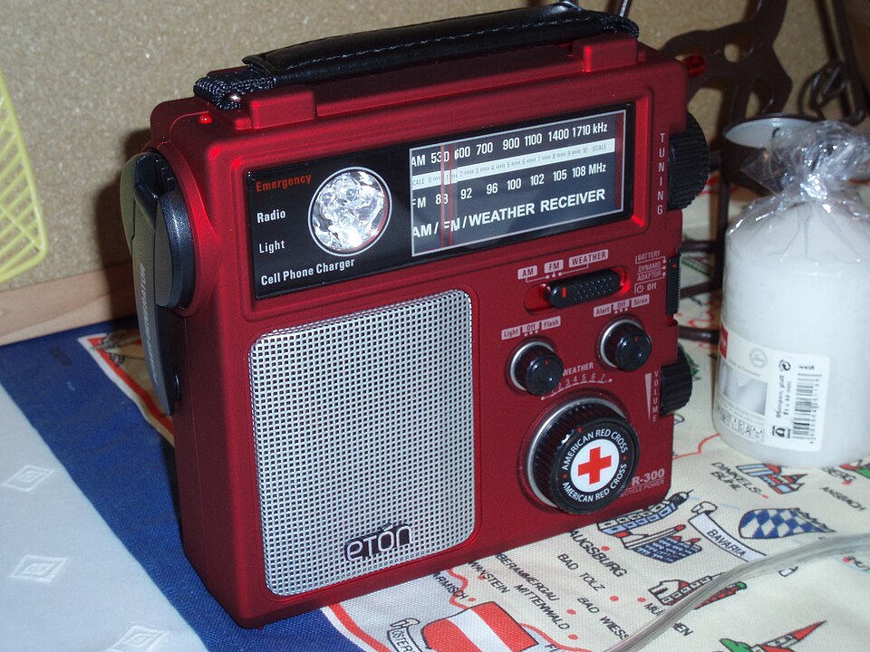 A red Eton emergency radio with a tuning dial, speaker grille and hand crank, for storm prep in Cedar Rapids, IA