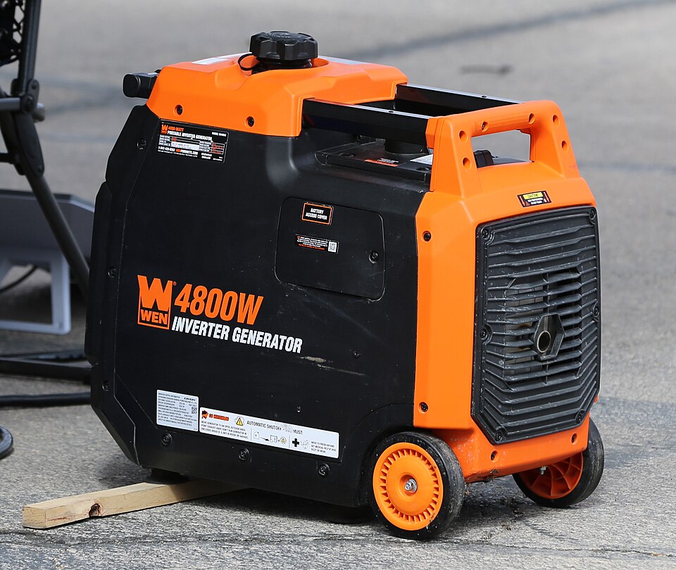 An orange and black WEN 4800 inverter generator with wheels, sitting on pavement, for storm prep in Cedar Rapids, IA